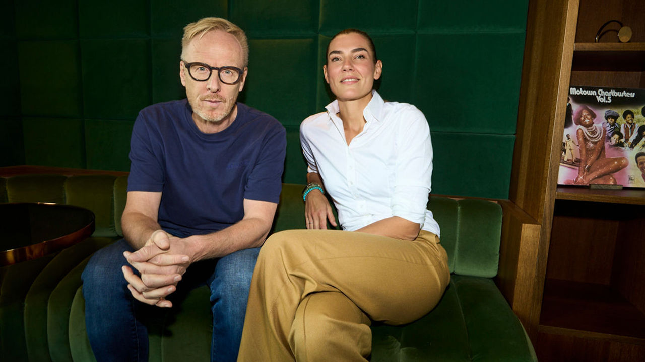 Das Bild zeigt Matthias Harbeck und Kathrin Jesse. Zwei Personen sitzen auf einem grünen Sofa; im Hintergrund ein Regal mit der Schallplatte „Motown Chartbusters Vol. 5“.
