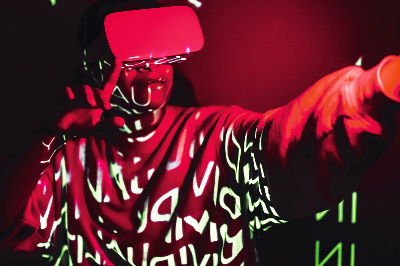 Crimson red technological concept with a person in VR glasses and Individuality projection. Vibrant tone of 2023 in gaming and esports concepts. Futuristic Metaverse in neon lights