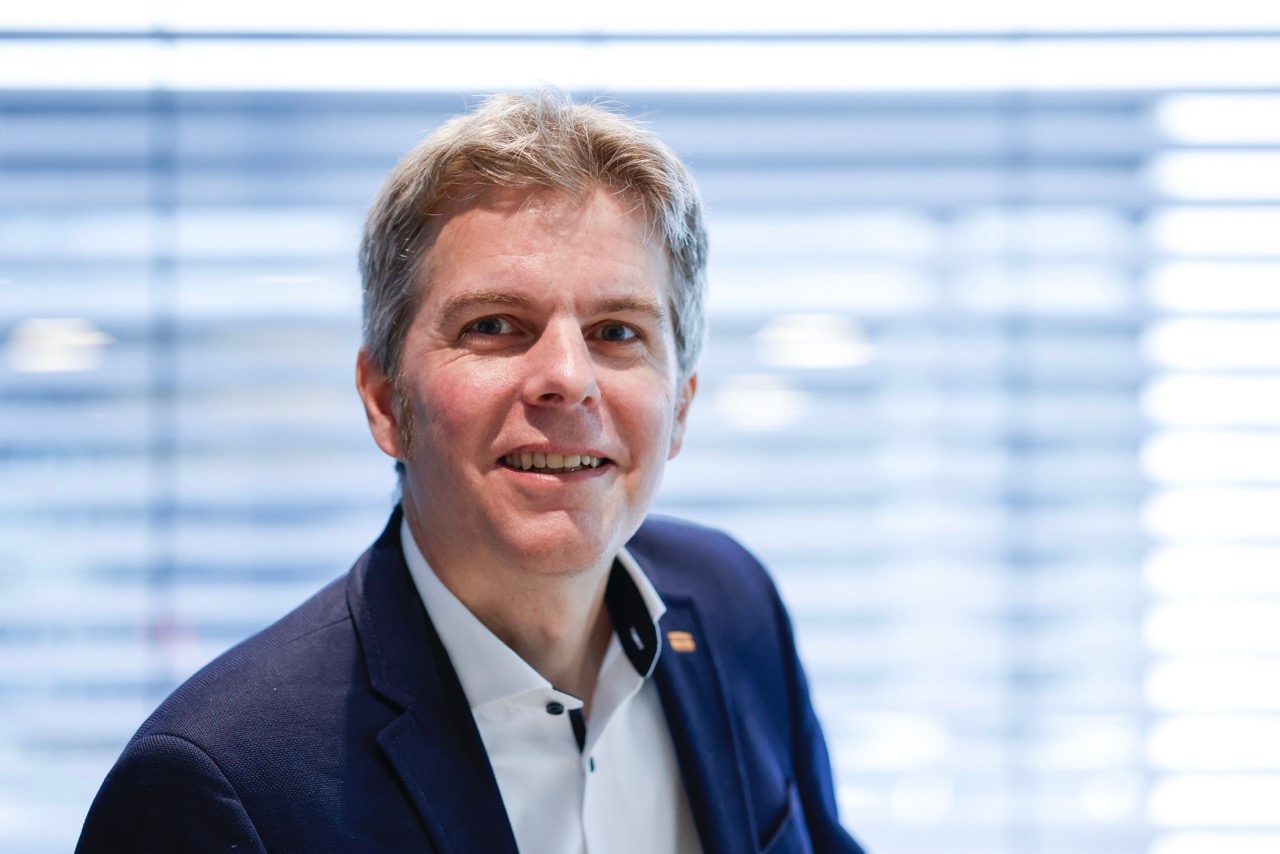 Prof. Christian Schmidkonz: The photo shows the head of a man, who has light hair and wears a navy blazer and white shirt.. He is smiling directly into the camera.